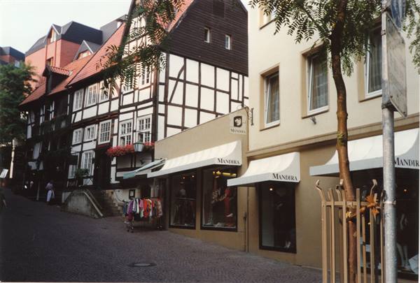 Half-timbered houses above a cobblestone slope, Mandura shop with white awnings below