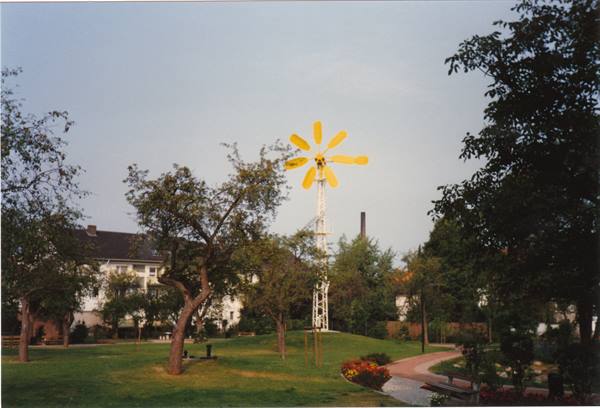Park with yellow sunflower-shaped windmill among trees and a path
