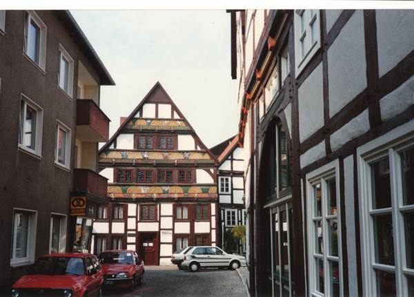 Painted half-timbered houses along a street with parked cars