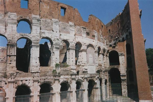 Travertine arches and brickwork of the Colosseum under Rome's blue sky