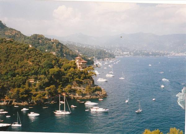 Boats anchored in Portofino bay, villa on the green cliff