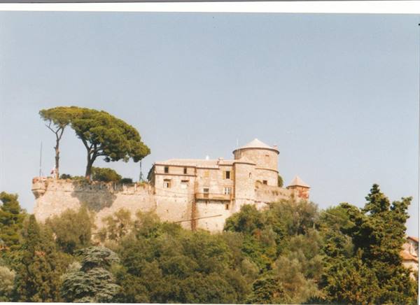 Castello Brown in Portofino, stone walls among pines and green trees, blue sky