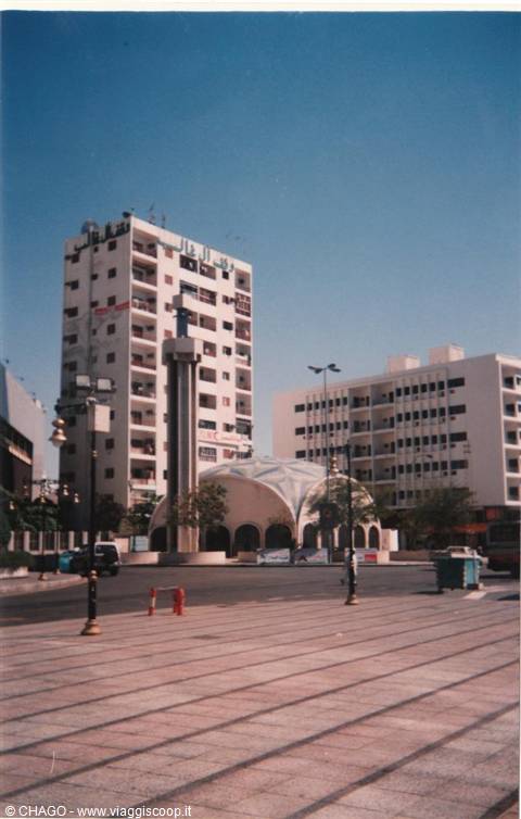 Tiled square with white dome and 1970s high-rises, blue sky