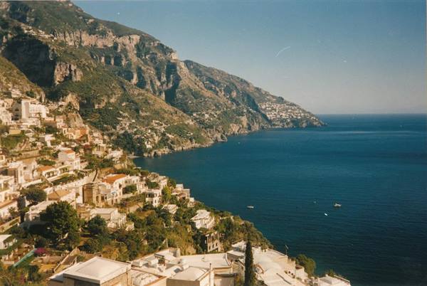 White houses of Positano on the cliff, blue sea below sunny mountains