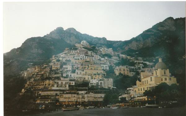 Positano, colorful houses stacked on the mountain and church dome at dusk