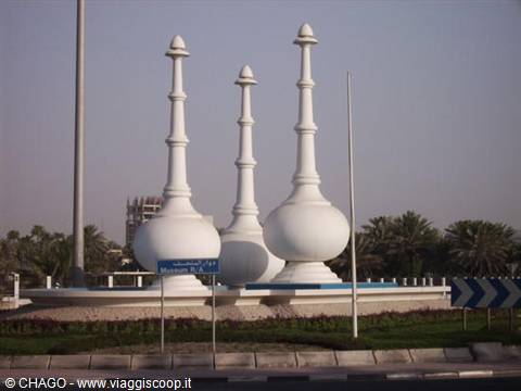 White incense burner monuments on a roundabout surrounded by palm trees