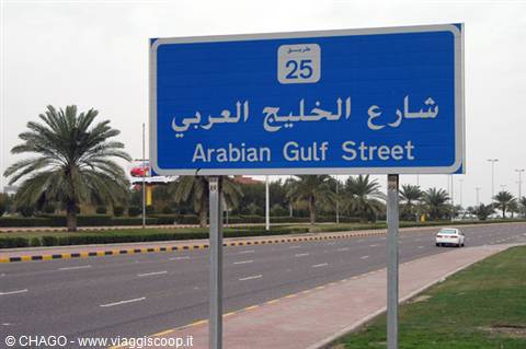 Bilingual blue road sign for Arabian Gulf Street along palm-lined road