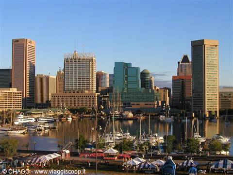 Baltimore Inner Harbor: skyscrapers above the marina, docked yachts, white tents in foreground