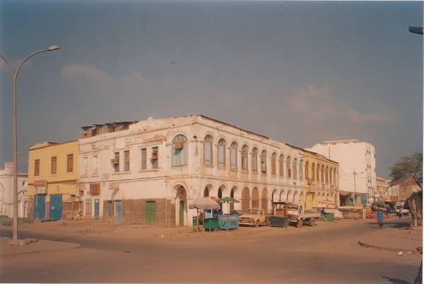 Colonial arcade building with closed shutters on sandy street with market stalls