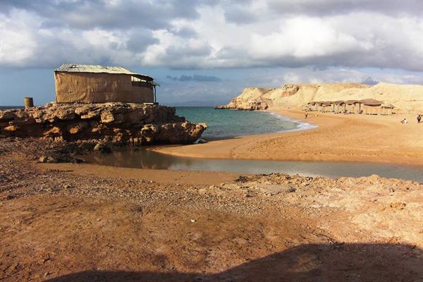 Brick hut on rocky cliff beside sandy beach and turquoise sea, Red Sea, Egypt