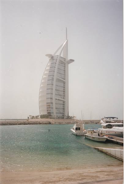 Burj Al Arab in haze, yachts moored at the dock by the beach