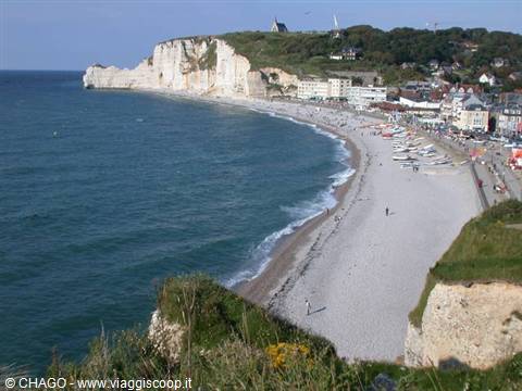 Étretat beach with white chalk cliffs, boats and sunny sea