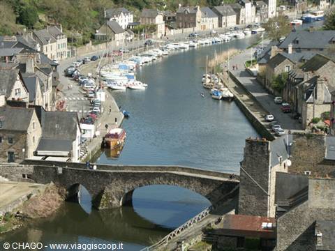 Old stone bridge over Dinan river harbor, boats moored among granite houses