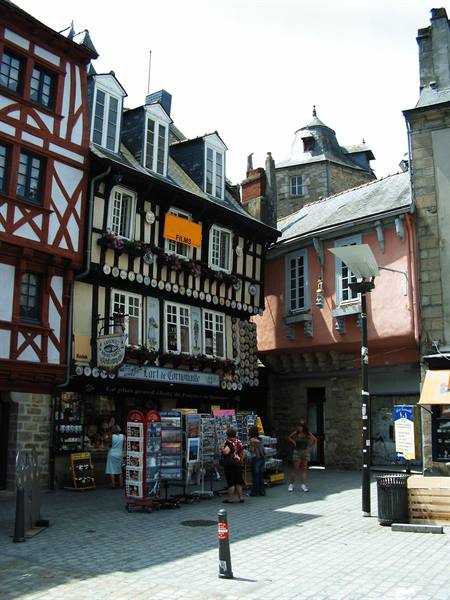 Medieval half-timbered houses in Quimper, tourists browsing postcard stands