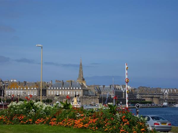 Colorful flowers in foreground, Saint-Malo walled town and spire under blue sky