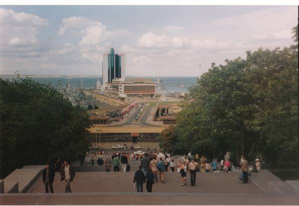 Crowded staircase descending to Odessa port, seaside tower under cloudy sky
