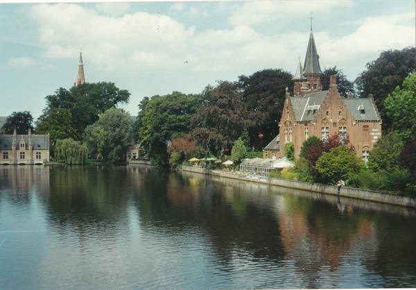 Minnewater lake in Bruges: brick buildings among trees, spires reflected on water