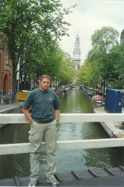 Tourist leaning on canal bridge railing, Zuiderkerk tower in Amsterdam