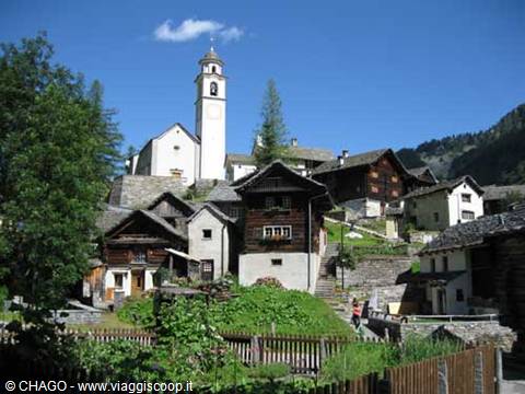 Alpine village with stone and wooden houses, white bell tower under blue sky