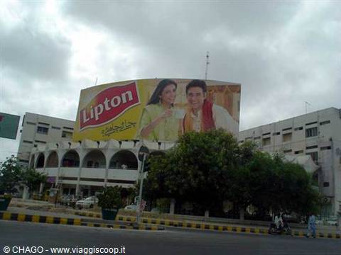 Huge yellow Lipton billboard above an arched building under cloudy sky