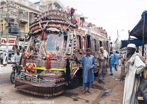 Men beside a colorfully decorated truck on a busy market street