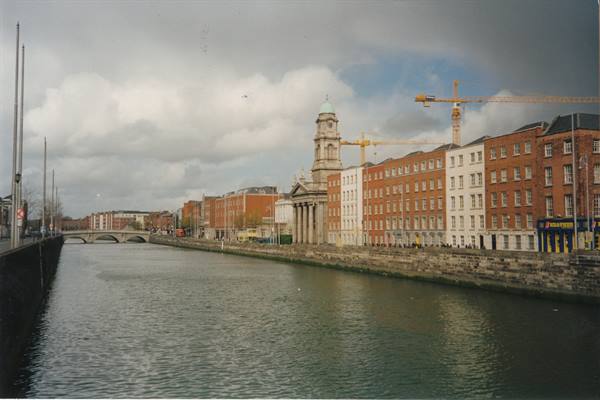 The River Liffey in Dublin with the Custom House and construction cranes under clouds
