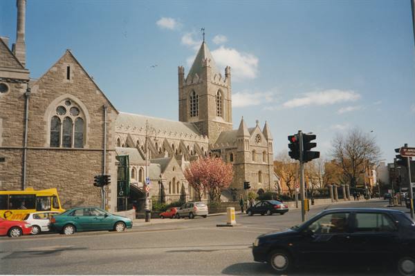 Christ Church Cathedral in Dublin, grey stone, traffic and traffic lights under sunny sky