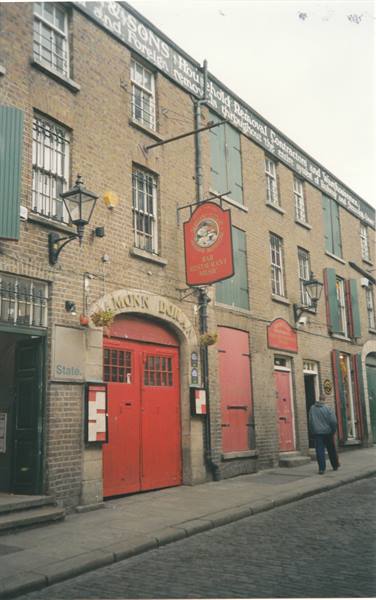 Brick facade with painted signage and red pub doors, man walking by