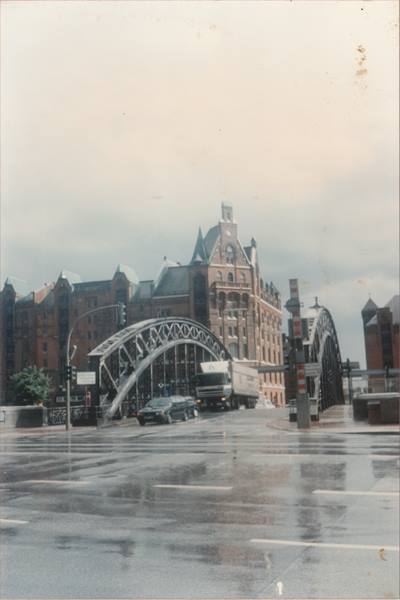 Truck and cars cross a steel bridge before Hamburg's brick warehouse buildings