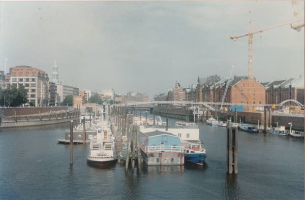 Boats moored at the harbor among red brick buildings and cranes