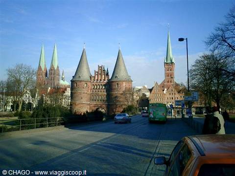 Holstentor red-brick gate with twin towers, cars and bus passing by in Lübeck