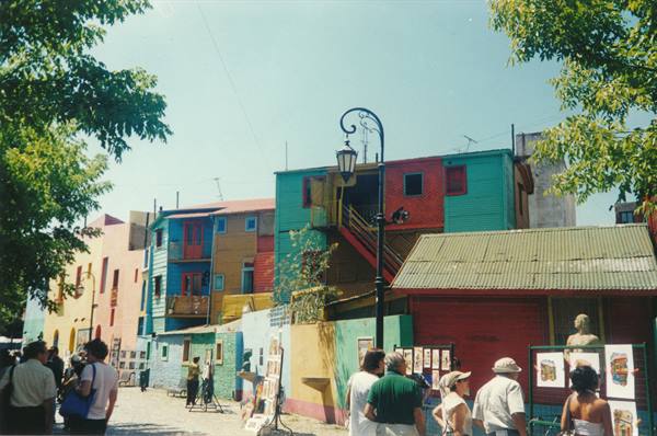 Colorful wooden and metal houses at Caminito, La Boca, tourists browsing paintings