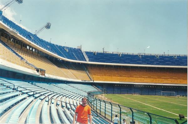 Man in orange shirt among blue and yellow seats at La Bombonera