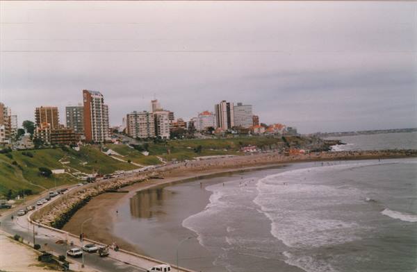 City beach with high-rise buildings on cliffs, waves over bathers