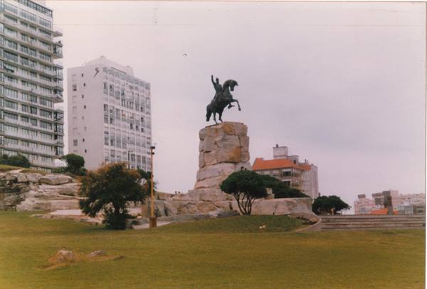 Bronze equestrian statue on granite rock among high-rise buildings, Punta del Este