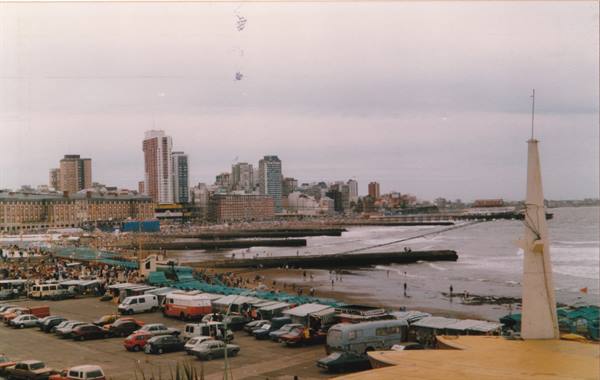 Crowded beach with coastal buildings and kites in the sky, Mar del Plata