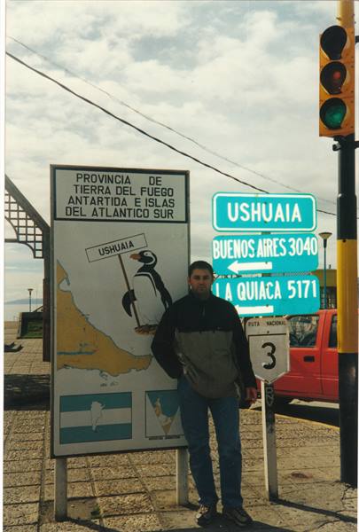 Man in front of Ushuaia sign with penguin and distance markers