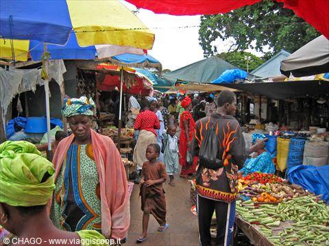 Open-air market with women in colorful headwraps, umbrellas and vegetable stalls
