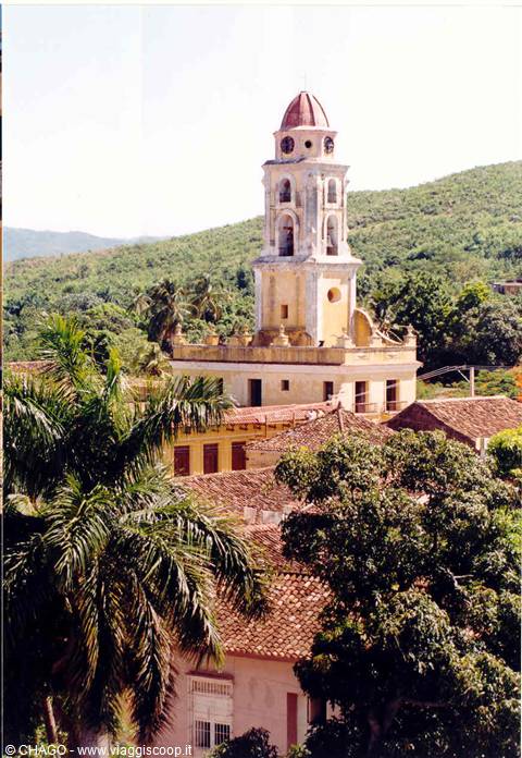 Yellow bell tower with red dome above Trinidad's rooftops and palm trees