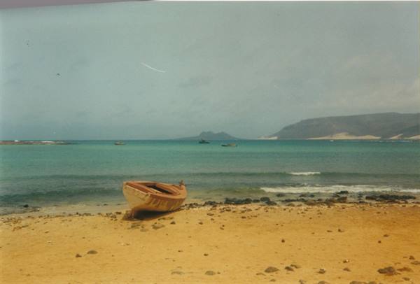 Wooden boat stranded on the sandy beach in front of turquoise sea