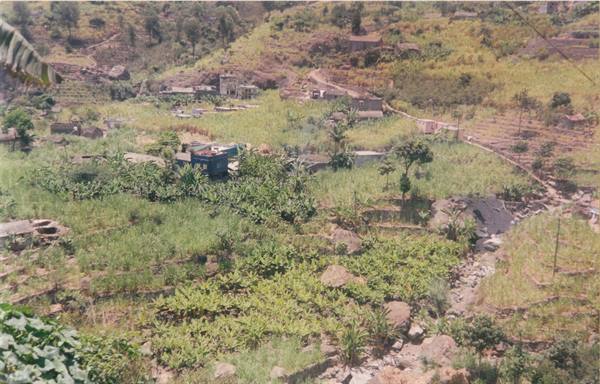 Rural village among cultivated fields and dry hills, scattered houses and green vegetation