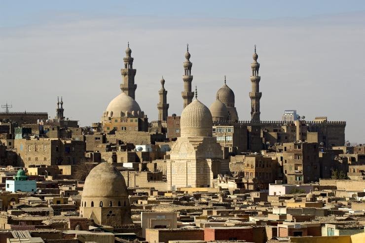 Minareti e cupole in pietra del Cairo islamico tra case basse