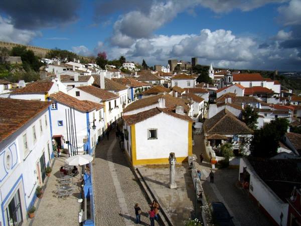 Whitewashed houses with blue and yellow trim, terracotta roofs in Óbidos