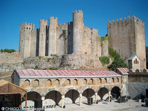 Medieval stone castle with crenellated towers above covered arches in Óbidos