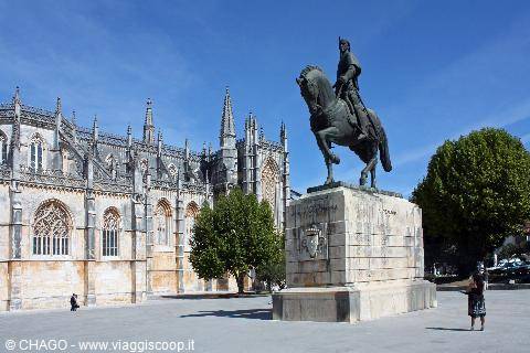 Bronze equestrian statue in front of Batalha Monastery pale stone Gothic facade