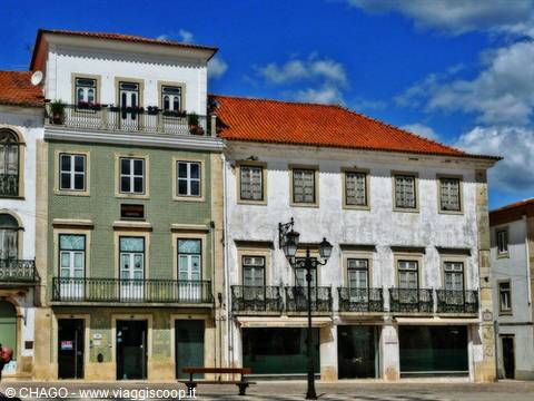Tiled facades with terracotta roofs on a sunny square, bench and lamppost
