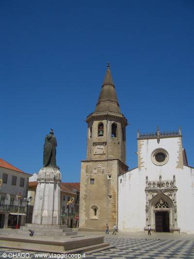 Statue and white church with conical bell tower in Tomar square