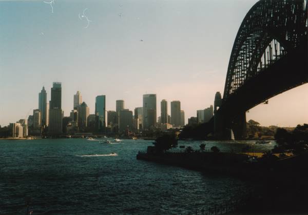 Sydney Harbour Bridge silhouetted over the bay, skyscrapers and ferries at dusk