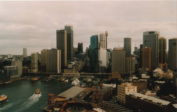 Skyscrapers above Sydney's Circular Quay, ferries manoeuvring beneath overcast skies