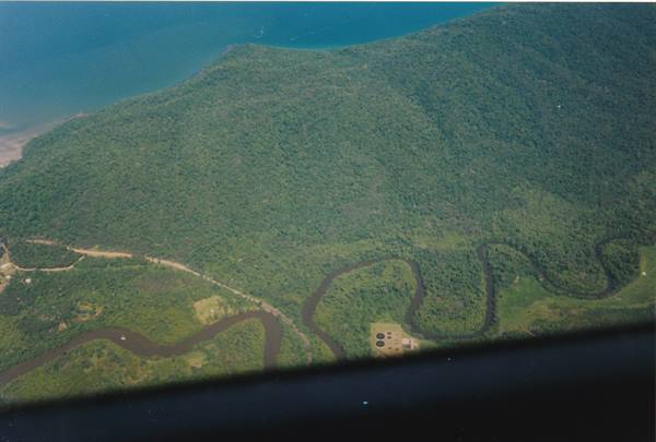 Winding river through green forest and turquoise coast, shot from airplane